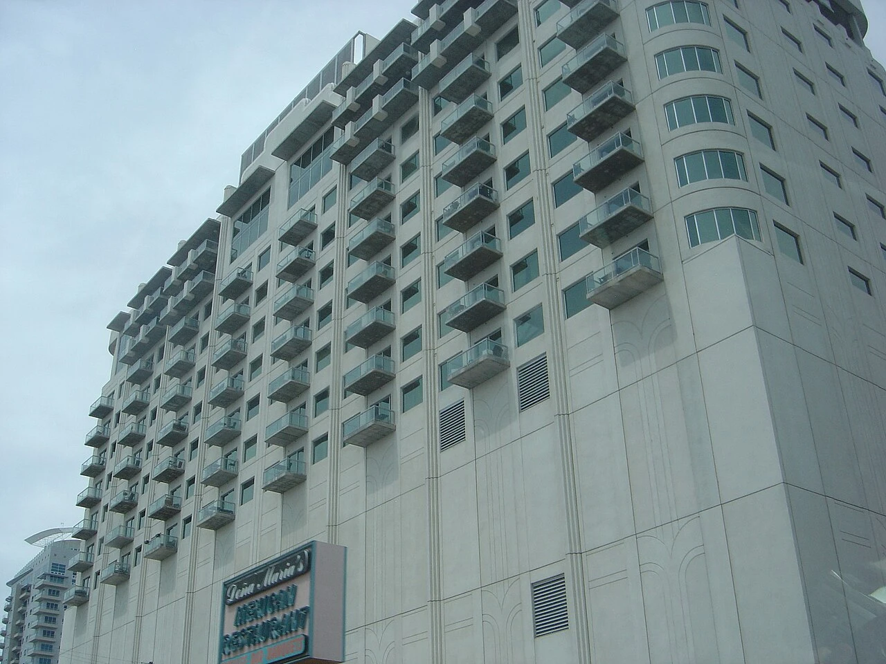 A white residential high rise with rows of glass balconies in downtown Las Vegas, seen from the street